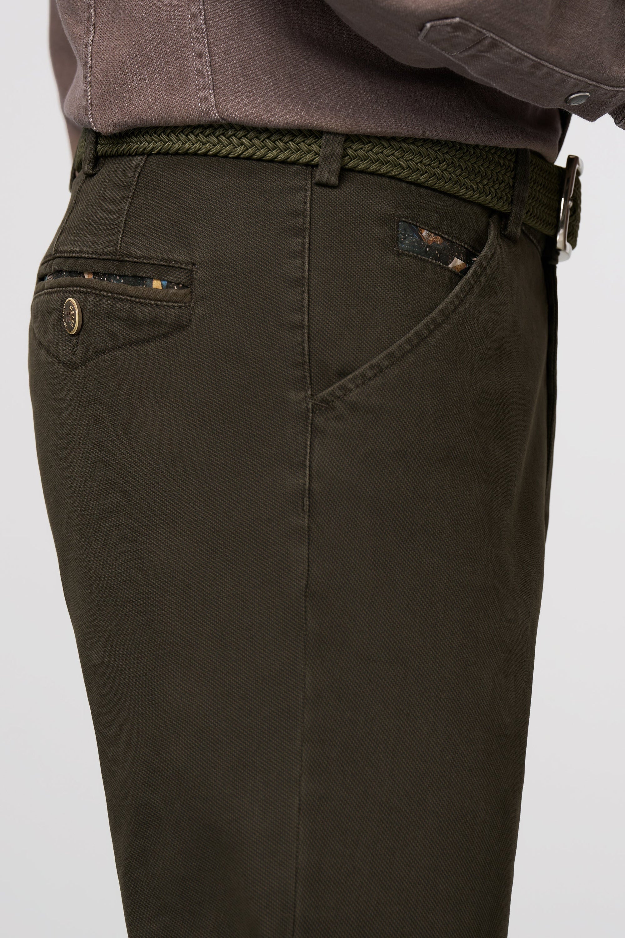 Dark green pants with a belt on a light gray background