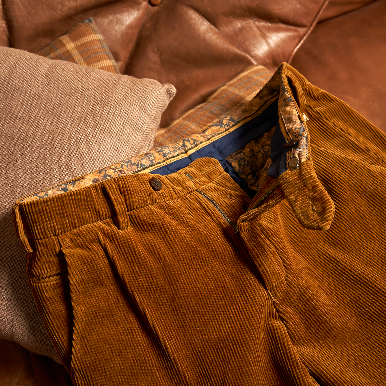 Brown corduroy pants with patterned lining on a brown leather couch.